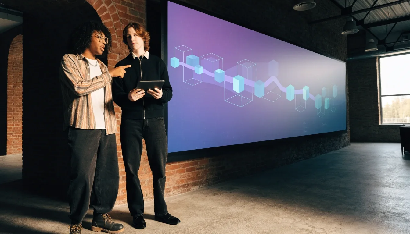 Two developers reviewing a deployment pipeline together in a Seattle studio workroom